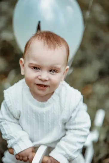 תינוקת מחייכת בין פרחים בגובה העיניים